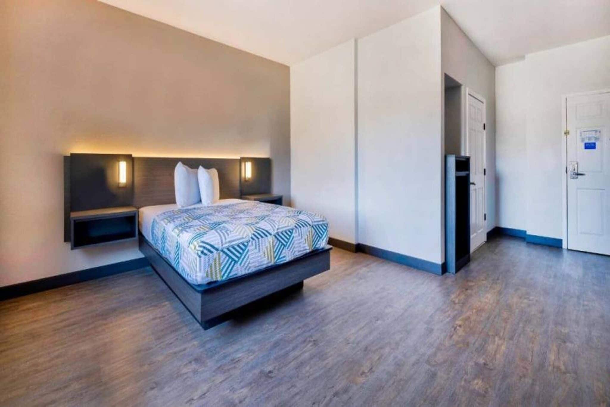 Quarto de hotel moderno com cama, mesas de cabeceira e guarda-roupa.