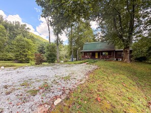 A cabin with a porch, surrounded by trees and a gravel path. - Mountain Cabin | Hot Tub & Deck | Mountain Views (Tiger)