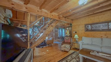 Un interior de madera con una escalera, un televisor, un sofá y una lámpara.