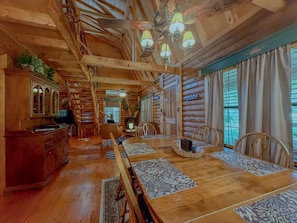 A log cabin interior with a dining area, wooden furniture, and a chandelier. - Mountain Cabin | Hot Tub & Deck | Mountain Views (Tiger)