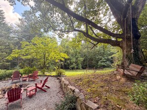 A forested area with a swing set and red Adirondack chairs. - Mountain Cabin | Hot Tub & Deck | Mountain Views (Tiger)