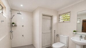 A bathroom with a shower, toilet, sink, and a window with a view. - PiyaSewana Spice Garden Villa is located close to Colombo Katunayake Airport, (Banduragoda)