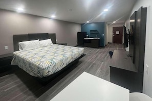 Una habitación de hotel moderna con una cama grande, un escritorio, una silla y un armario.