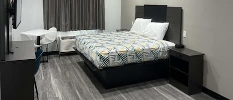 A modern hotel room with a bed, bedside tables, a desk, and a chair.