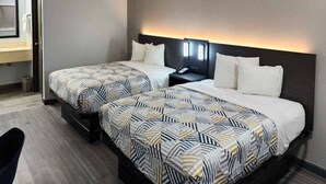 Une chambre d’hôtel avec deux lits, une table de chevet, un bureau et une chaise.