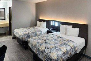 Een hotelkamer met twee bedden, een nachtkastje, een bureau en een stoel.