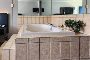 A modern bathroom with a large bathtub, a sink, and a mirror.