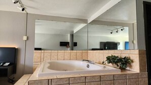 Et moderne badeværelse med et stort badekar, et spejl og en potteplante.