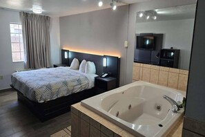 Une chambre d’hôtel avec un lit, une grande baignoire, une télévision et une fenêtre avec des rideaux.
