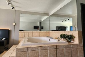 Une salle de bain moderne avec une grande baignoire, un miroir et une plante en pot.