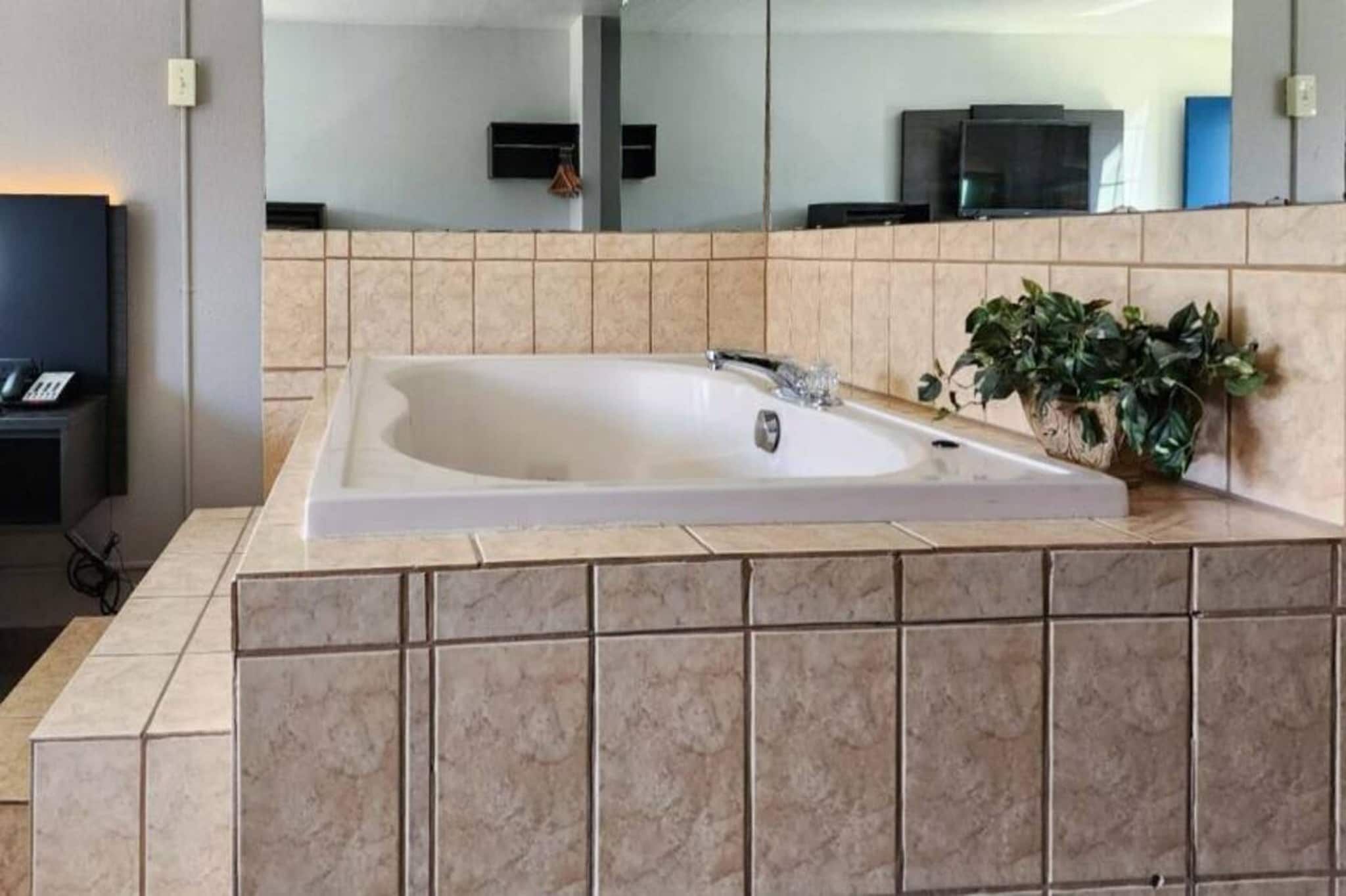 A modern bathroom with a large bathtub, a sink, and a mirror.