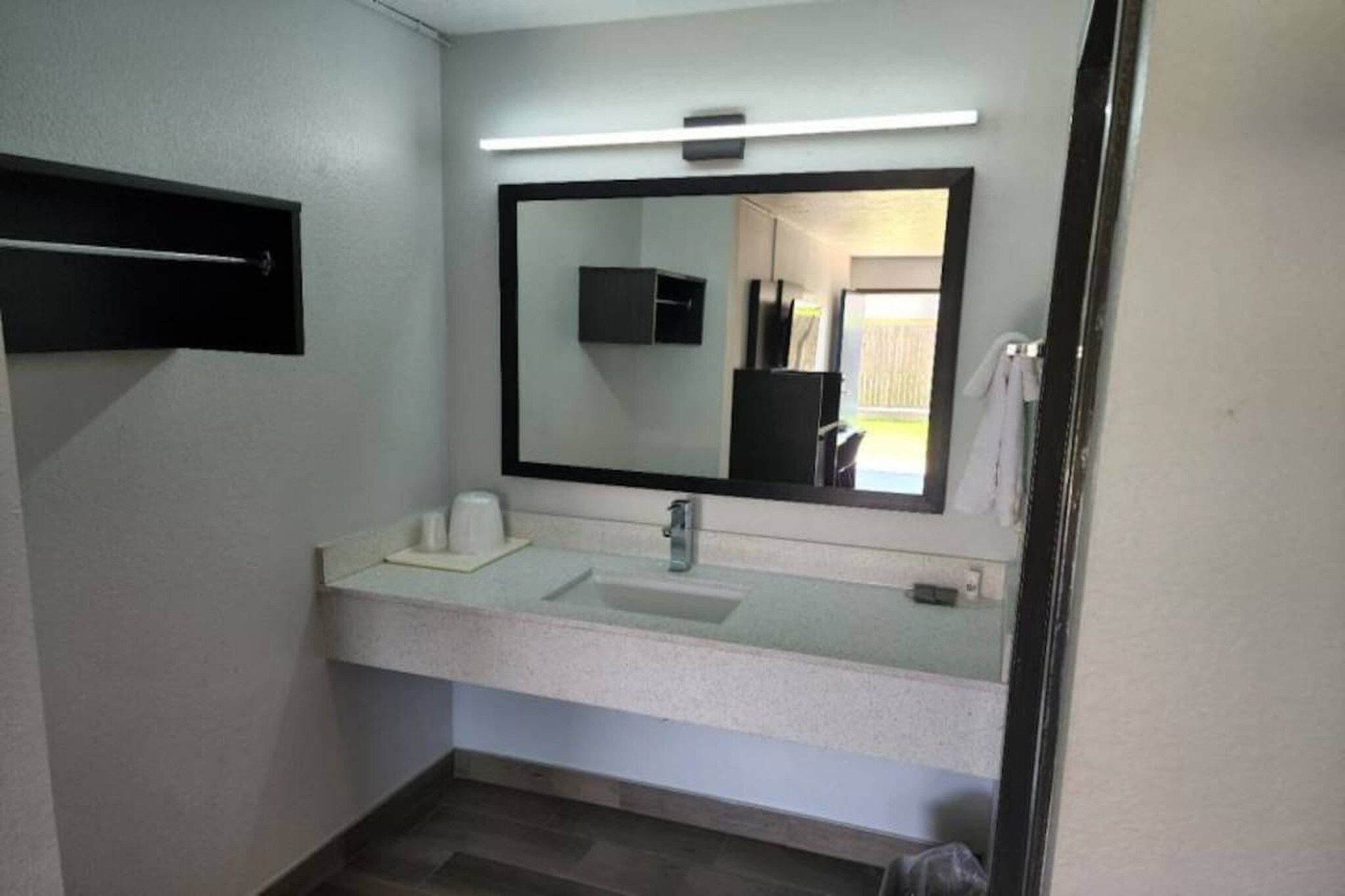 A bathroom with a white sink, a mirror, and a towel rack.