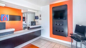 Zona d'adreça d'hotel amb un taulell, una pantalla de televisió i un panell informatiu digital.