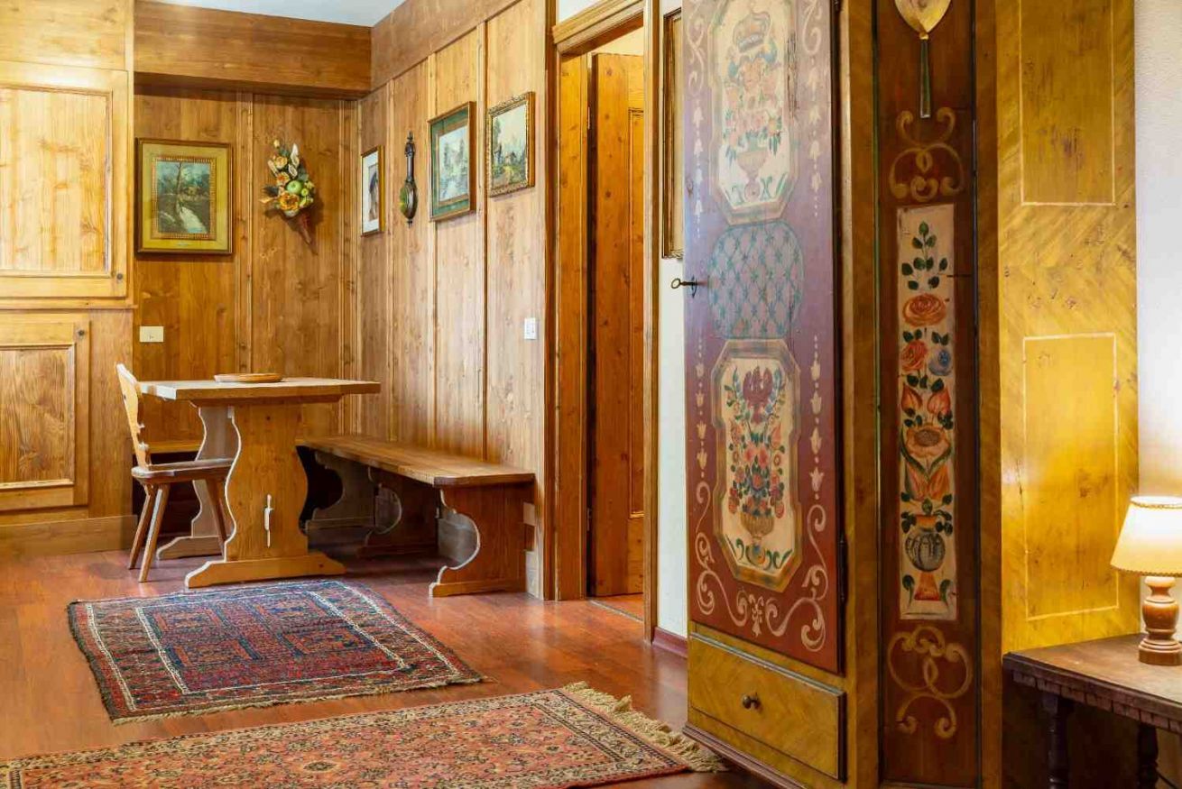 Un interior de madera con un banco, una mesa y una alfombra estampada.