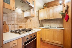 Una cocina con muebles de madera, estufa a gas y lavamanos.
