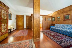 Una habitación con pisos de madera, un sofá azul con estampado y alfombras tradicionales.