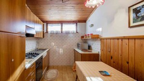 A compact kitchen with wooden cabinets, a stove, and a microwave. - Apartment for 5 with Panoramic Terrace Near Cortina Centre (Cortina d'Ampezzo)