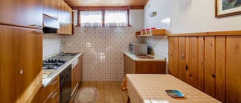 A compact kitchen with wooden cabinets, a stove, and a microwave.