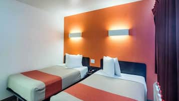 Habitación de hotel con dos camas individuales, una mesita de noche y una lámpara de pared.