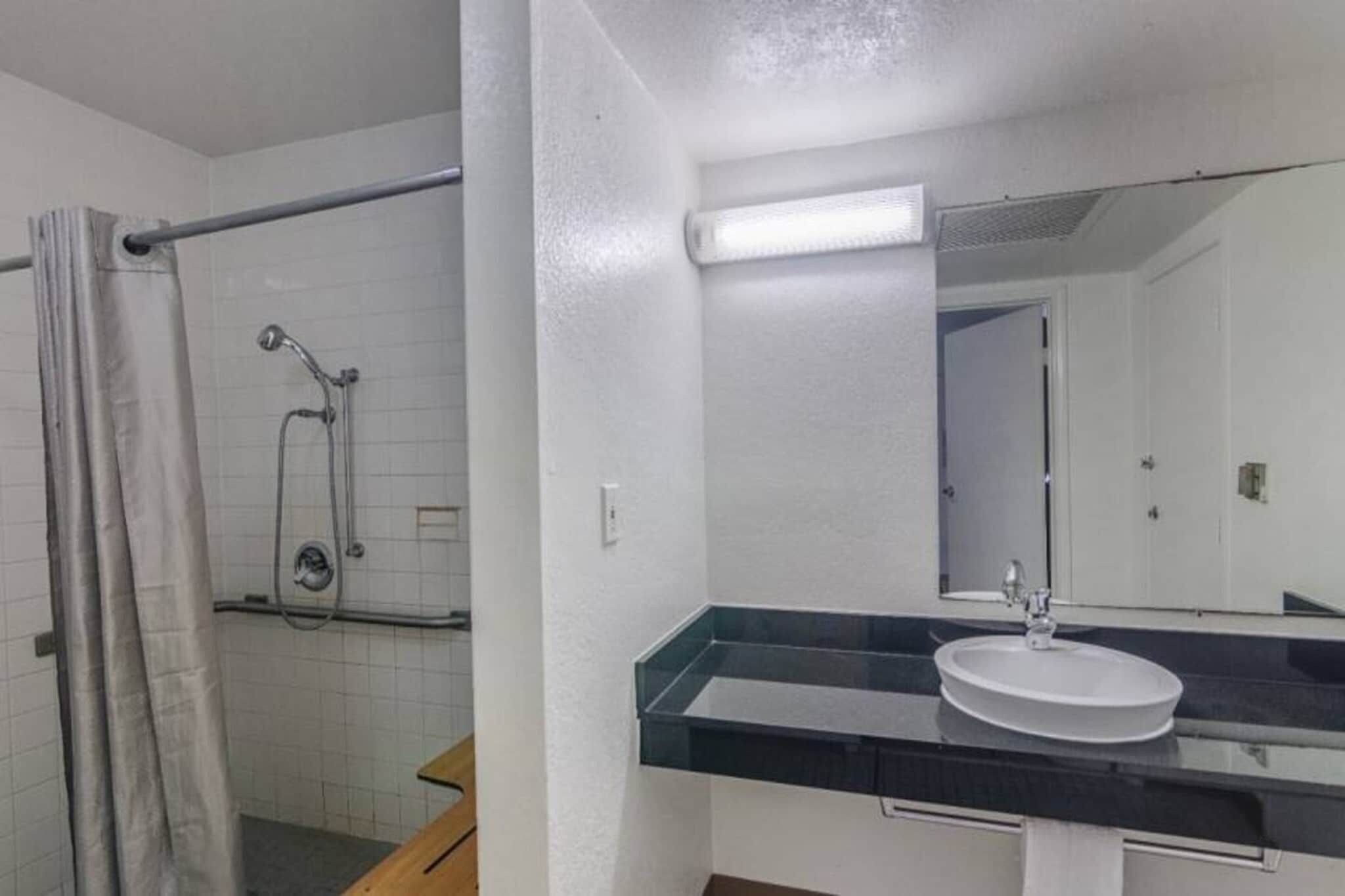 Ein Badezimmer mit Dusche, Waschbecken und Spiegel.