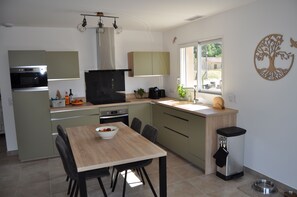 A modern kitchen with a dining table, chairs, and a window. - Charming vacation rental: pool, stunning view, dogs welcome, enclosed garden, near Nyons. (Curnier)