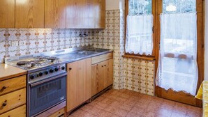 Una cocina con gabinetes de madera, estufa a gas, pileta y azulejos con diseño.