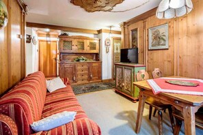 Una habitación acogedora con sofá, armario de madera y una mesa de comedor con sillas.