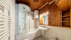 Een moderne badkamer met een douchecabine, een bad, een wastafel en een toilet.