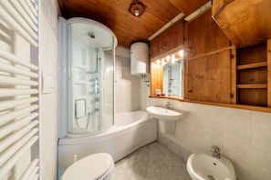 Un baño moderno con ducha envuelta en cristal, bañera, lavamanos y un bidé.