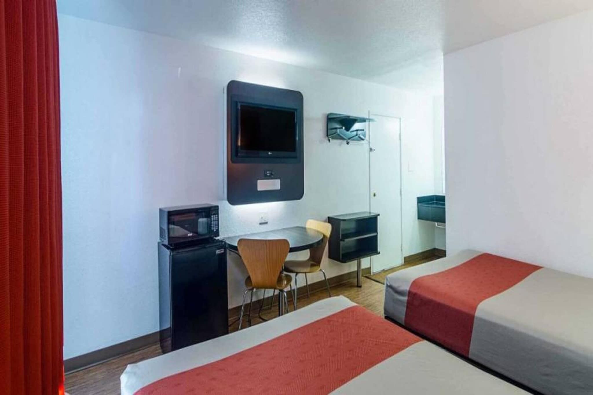 Habitación de hotel con dos camas, un escritorio, una silla, un televisor y un minibar.