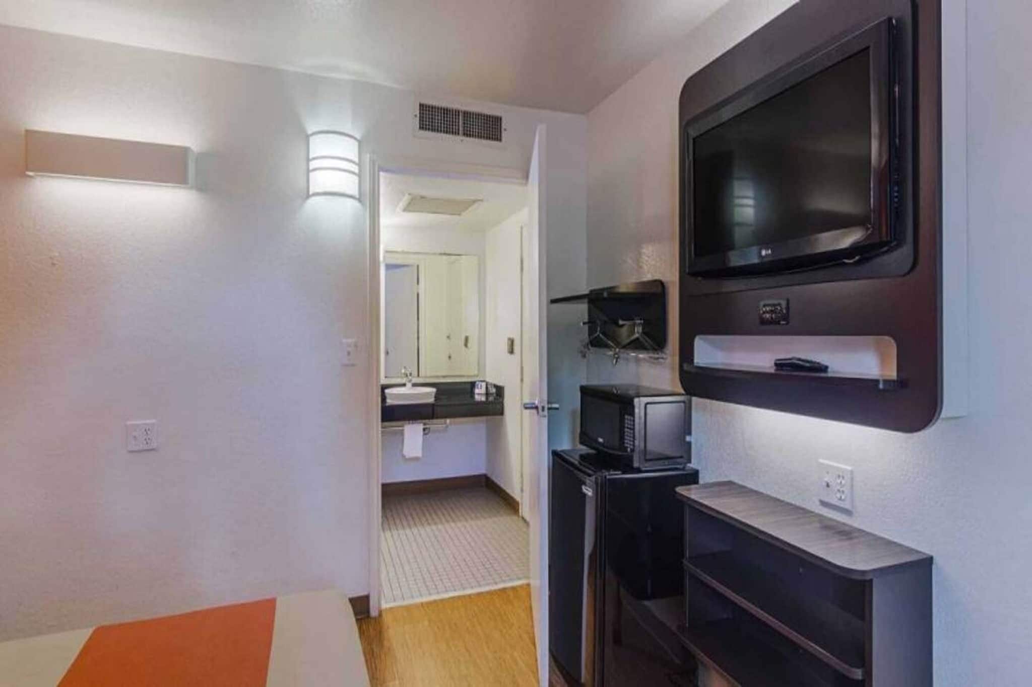 Habitación de hotel con televisión, microondas y pequeña zona de kitchenette.