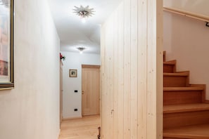 Un corridoio con pavimento in legno, una scala in legno e una porta con un piccolo quadro appeso al muro.