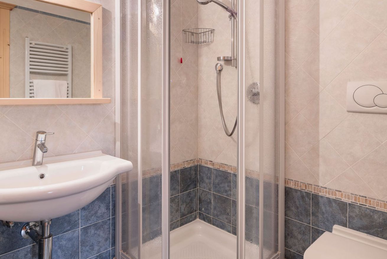 A bathroom with a glass-enclosed shower, a white sink, and a mirror above it.