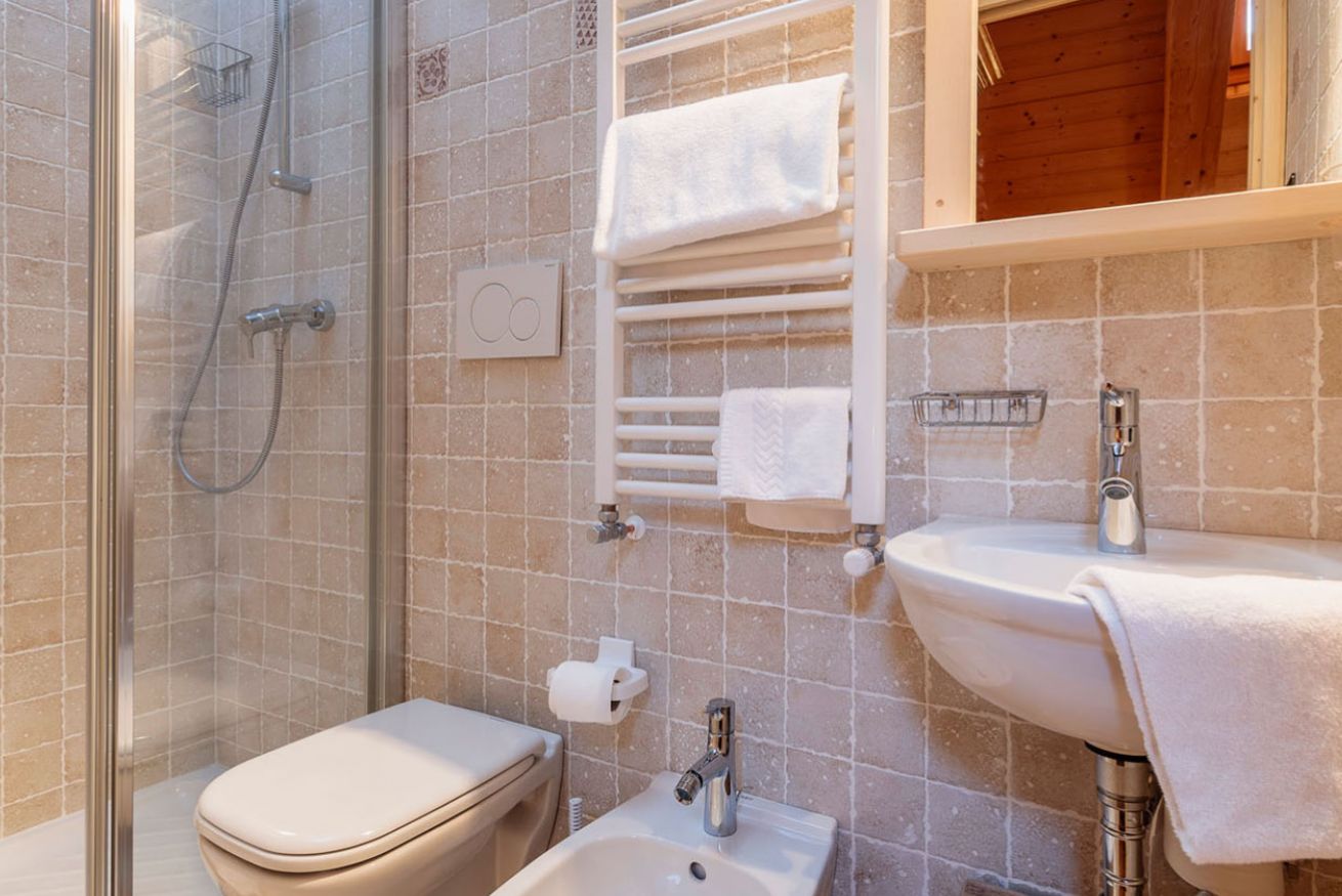 A bathroom with a glass-enclosed shower, a toilet, a sink, and a towel rack.