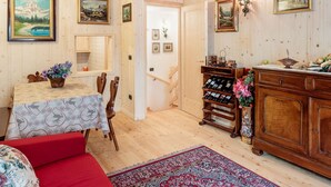 En inredning med träpanel, ett matområde, en soffa, ett vinställ och inramade tavlor på väggarna.