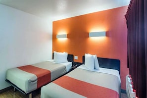 Een hotelkamer met twee enkele bedden, een nachtkastje en een wandlamp.