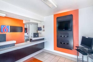Ein Hotel-Empfangsbereich mit einer Rezeption, einem Fernseher und einem digitalen Bildschirm.