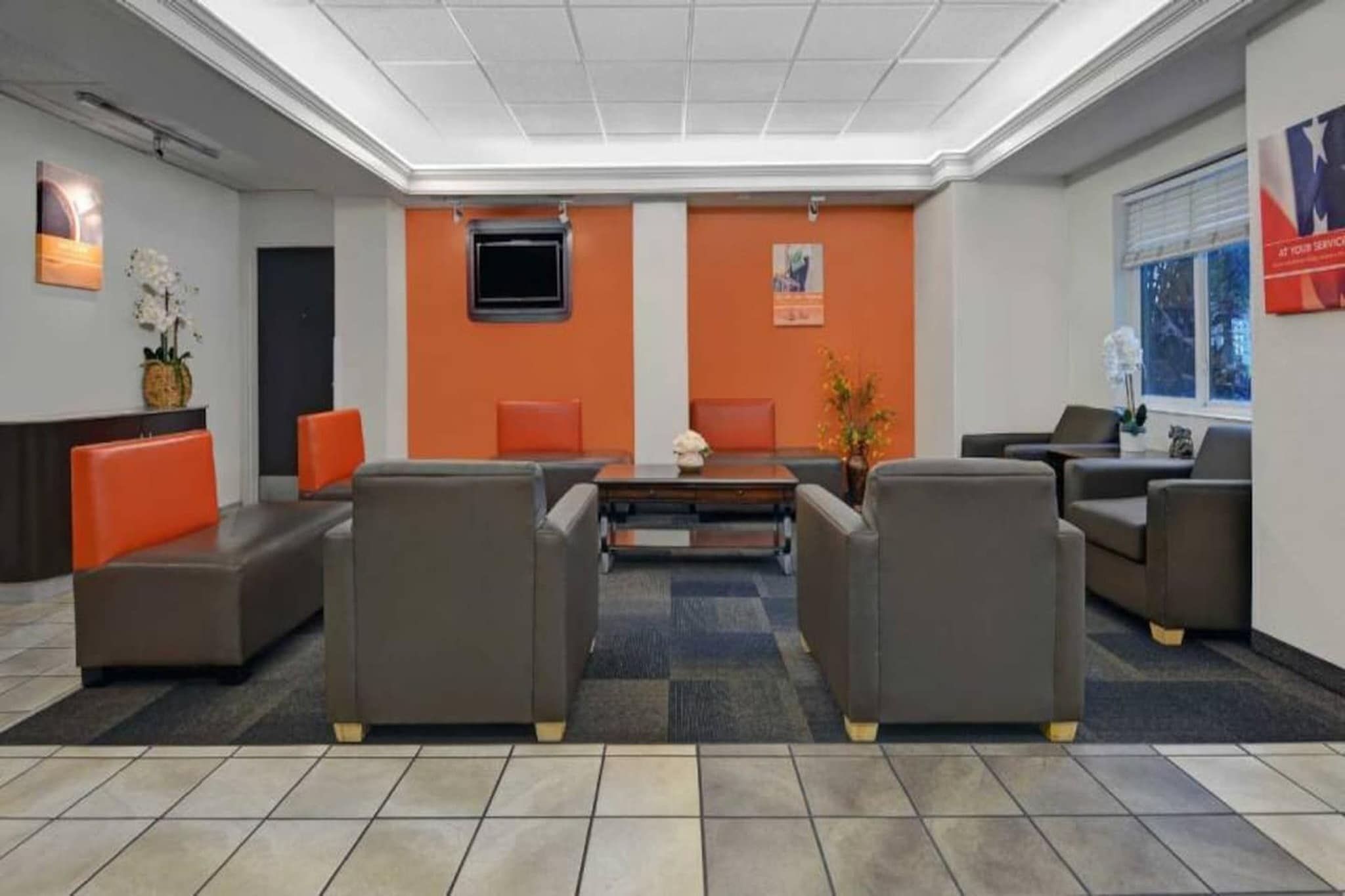 A lobby with a reception desk, seating area, and a large window.