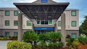 A hotel with a covered entrance, multiple windows, and a 'Welcome' sign. - 2 Full Beds | Premium, Mini Fridge (Orlando FL)