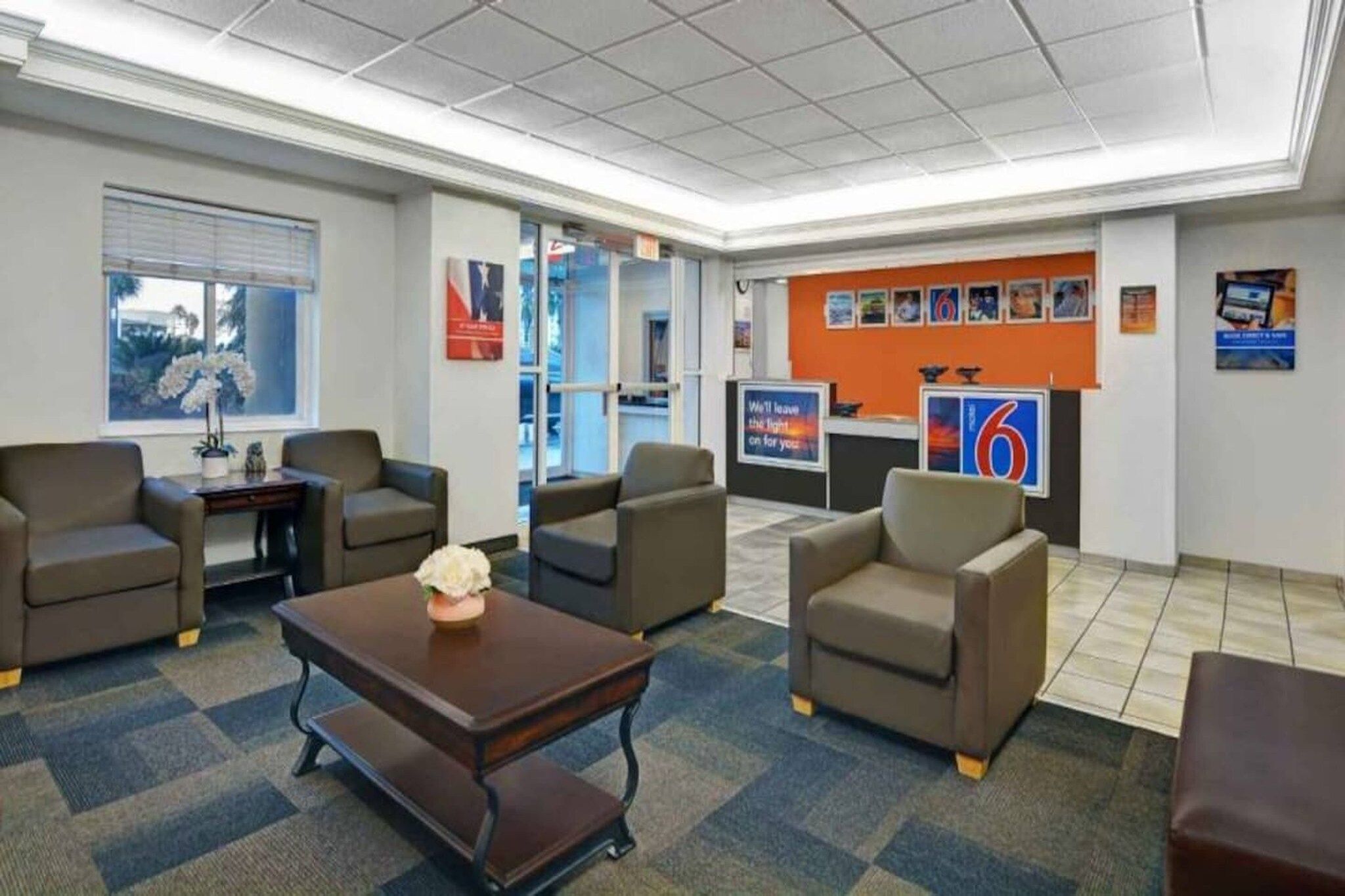 A lobby with seating, a reception desk, and a large wall with various posters.