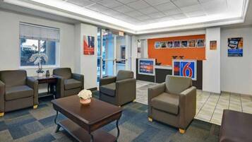 A lobby with seating, a reception desk, and a large wall with various posters.