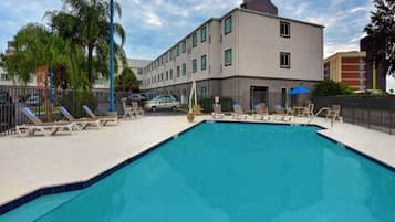 A swimming pool with lounge chairs and a building in the background.