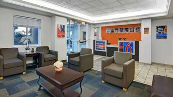 A hotel lobby with a reception desk, seating area, and a large window.