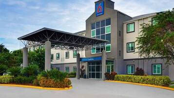 A modern hotel with a covered entrance, multiple windows, and a '6' sign indicating the building's name.