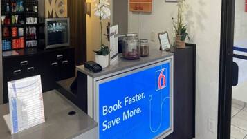 Un comptoir d’accueil d’hôtel doté d’un écran numérique affichant un message promotionnel.