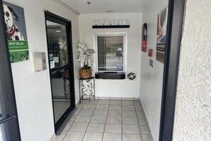 Ein Flur mit einem 'Welcome'-Schild, einem Fenster mit Jalousien, einer Tür und einem 'SPOT RELAX'-Schild.
