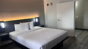 Quarto de hotel com cama, mesas de cabeceira, luminária na parede e guarda-roupa.