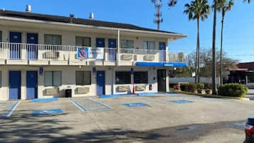A two-story motel with a blue and white color scheme, a parking lot with handicapped parking spaces, and a 'Weekly Specials' sign.