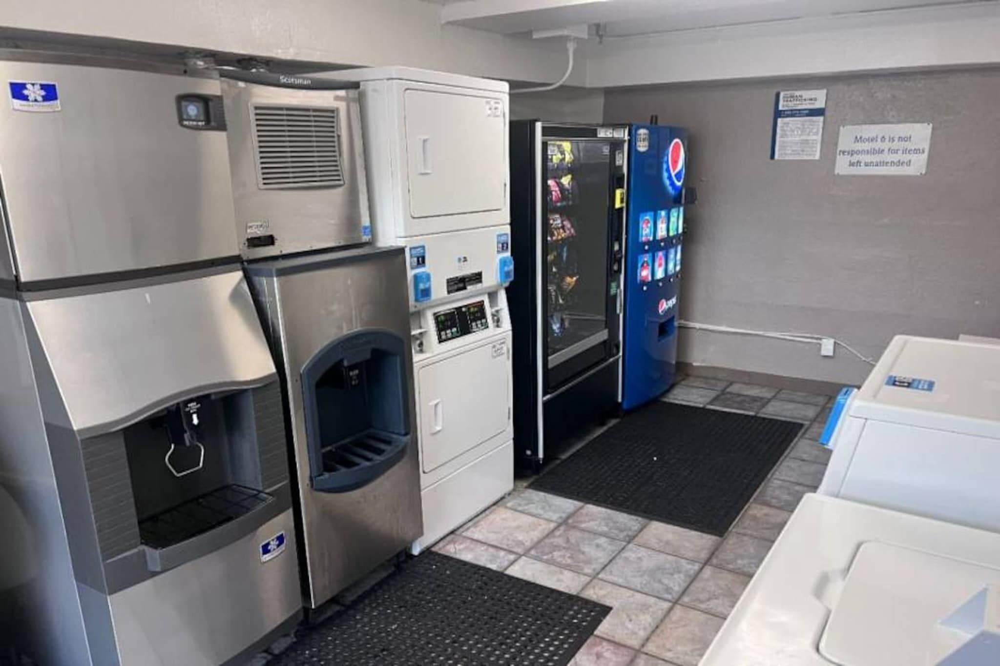 A commercial kitchen with stainless steel appliances, a vending machine, and a sign indicating the area is not for unattended items.