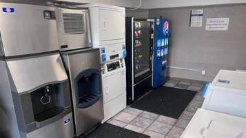 A commercial kitchen with stainless steel appliances, a vending machine, and a sign indicating the area is not for unattended items.